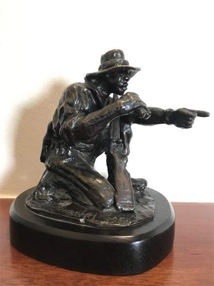 Bronze sculpture of a safari guide pointing, awarded for excellence.