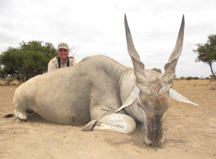 Zimbabwe Hunting Tourist with dead antelope in African safari landscape.
