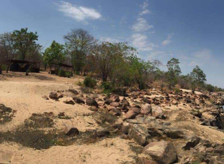 Mozambique Hunting Scenic view of a river in an African safari landscape with trees and rocky terrain.