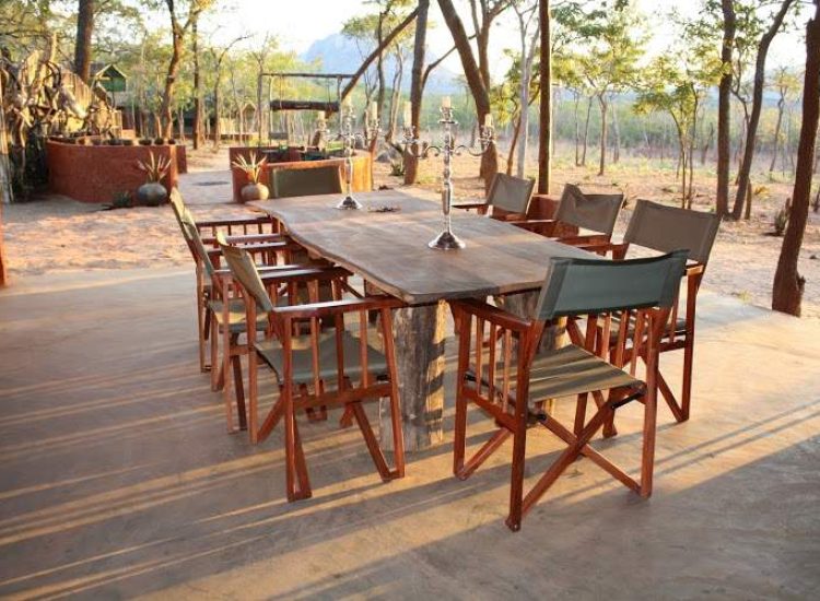 Mozambique Hunting Outdoor dining setup with wooden table and chairs in a natural setting.