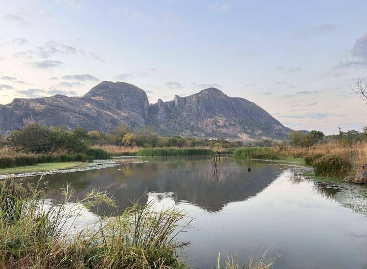Mozambique Hunting Scenic mountain landscape with river and lush vegetation in the foreground.
